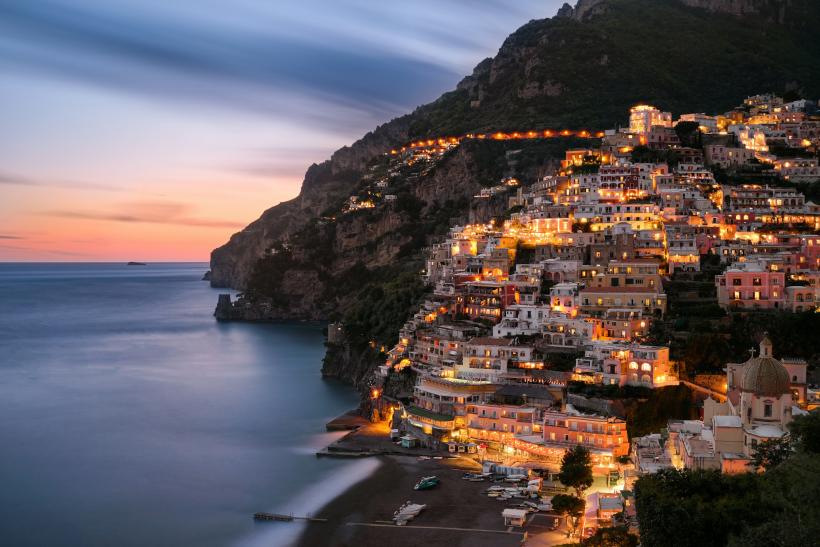 Farebné domy a pláž v Positano po západe slnka.