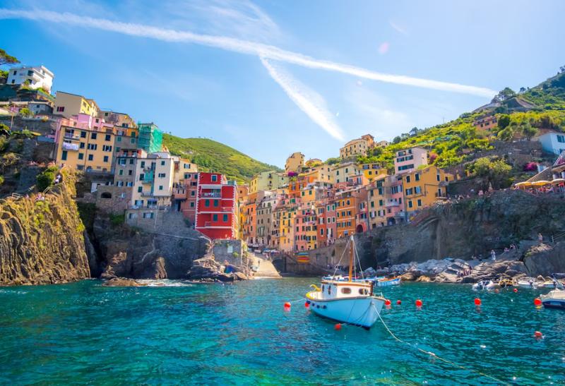 Riomaggiore s farebnými domami a prístavom s loďkou na mori.