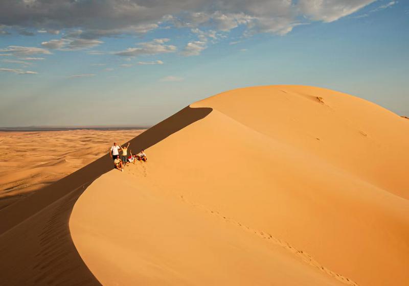 Piesková duna a turisti v Mongolsku.