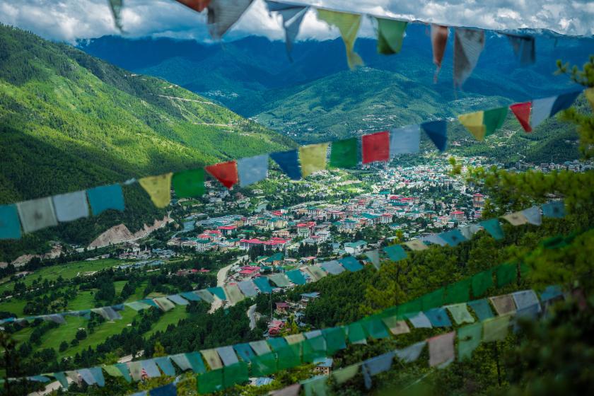 Pohľad z výšky na farebné domy a zelené kopce mesta Thimphu v Butáne.