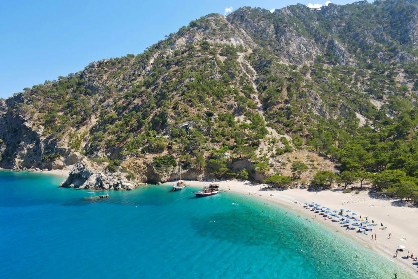 Smaragdové more na pláži Apella, piesok a male lode na ostrove Karpathos.