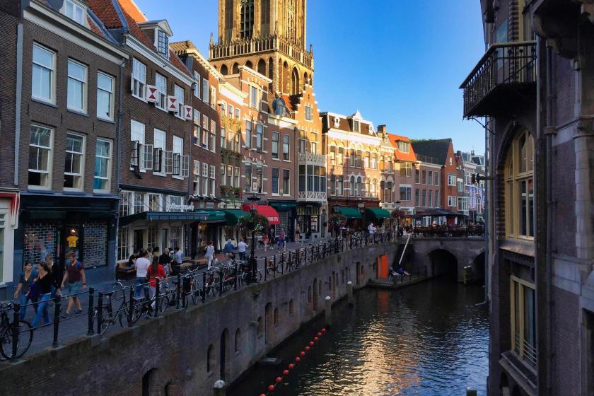 Vodný kanál, domy a ľudia na ulici v Utrechte.