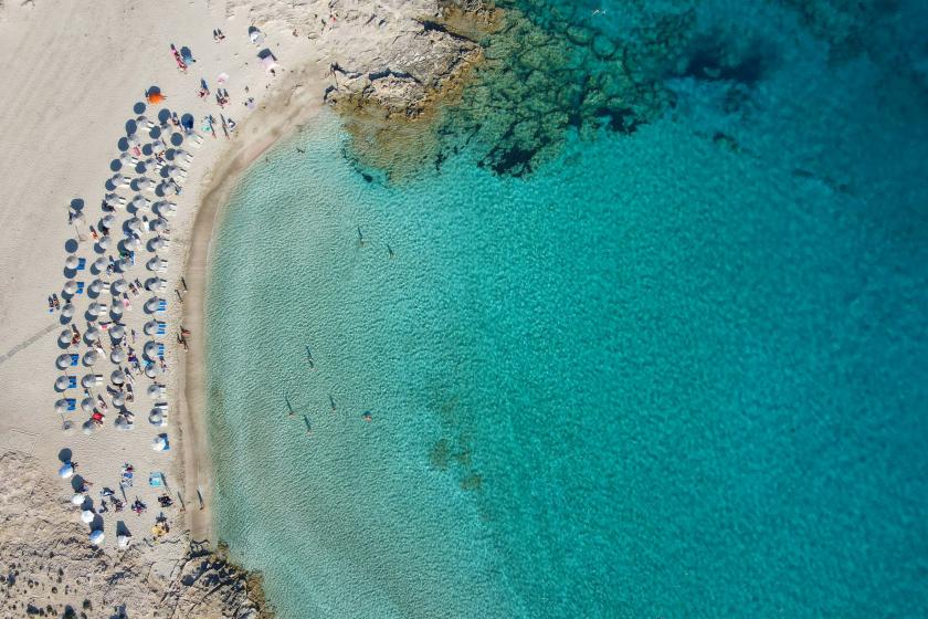 Tyrkysové more, lehátka a slnečníky na ostrove Karpathos.