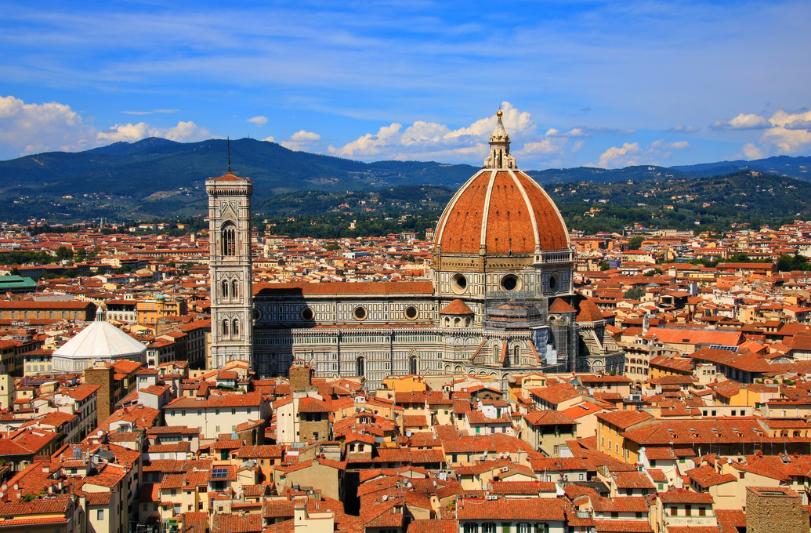 Katedrála, veža, červené strechy domov, v pohorie v pozadí. Florencia.
