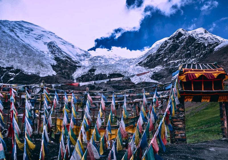 Zasnežené Himaláje, farebné vlajky a brána. Čína. Foto: unsplash.com