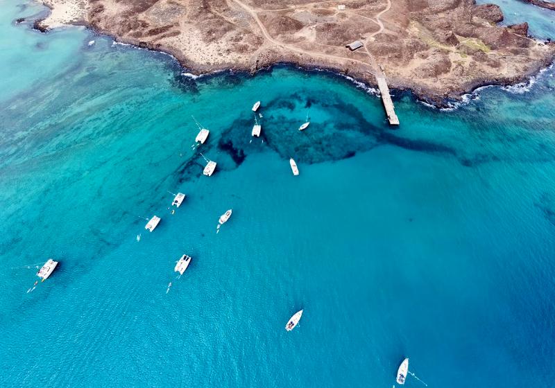 Tyrkysový oceán a  biele lode na drsnom pobreží Lanzarote. Kanárske ostrovy. Foto: unsplash.com