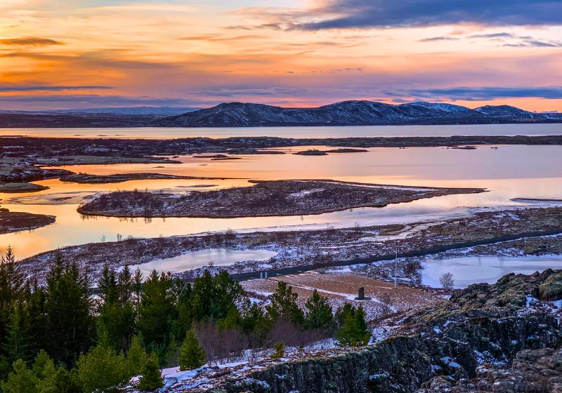 Stromy, more a kopce posiate snehom pri západe slnka v NP Tingvellir, Island. Foto: unsplash.com