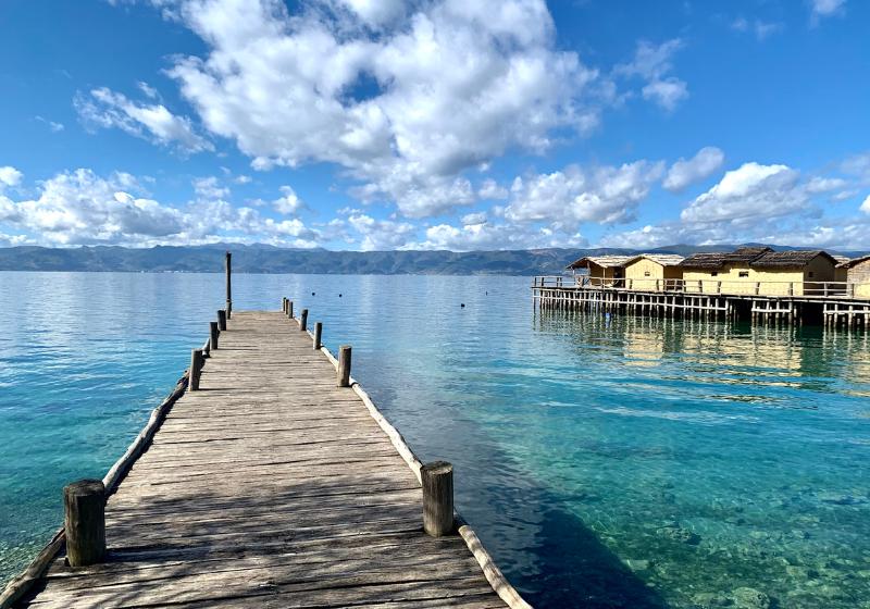 Jazero Ohrid s dreveným mólom a domami na vode.