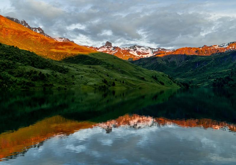 Jazero a okolité zelené kopce a  sklané štíty so snehom v Beafort. Francúzsko. Foto: unspalsh.com