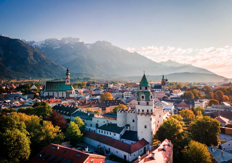 Stredoveké mesto Hall in Tirol s vežami, domami a horami v pozadí.
