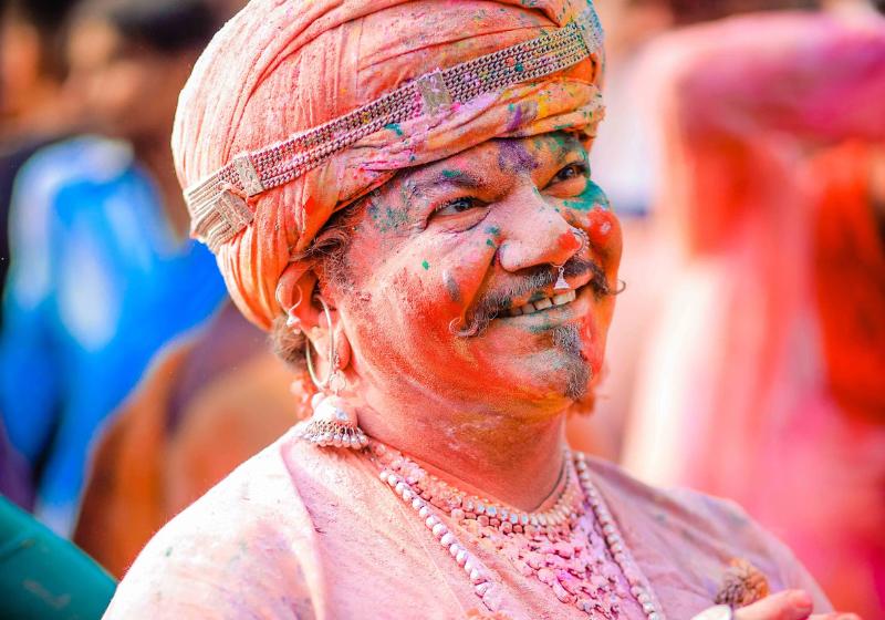 Muž s farebnou tvárou počas sviatku Holi v Indii.