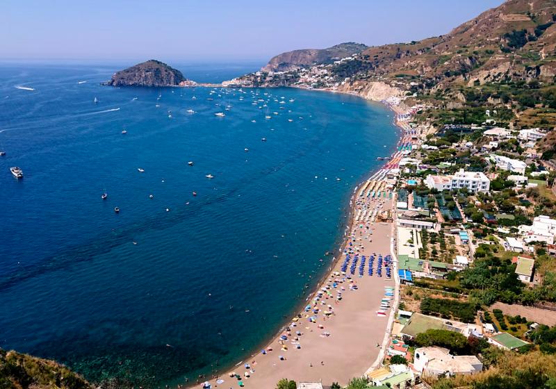 Piesková pláž s ľudmi a tyrkysové more na ostrove Ischia, Taliansko