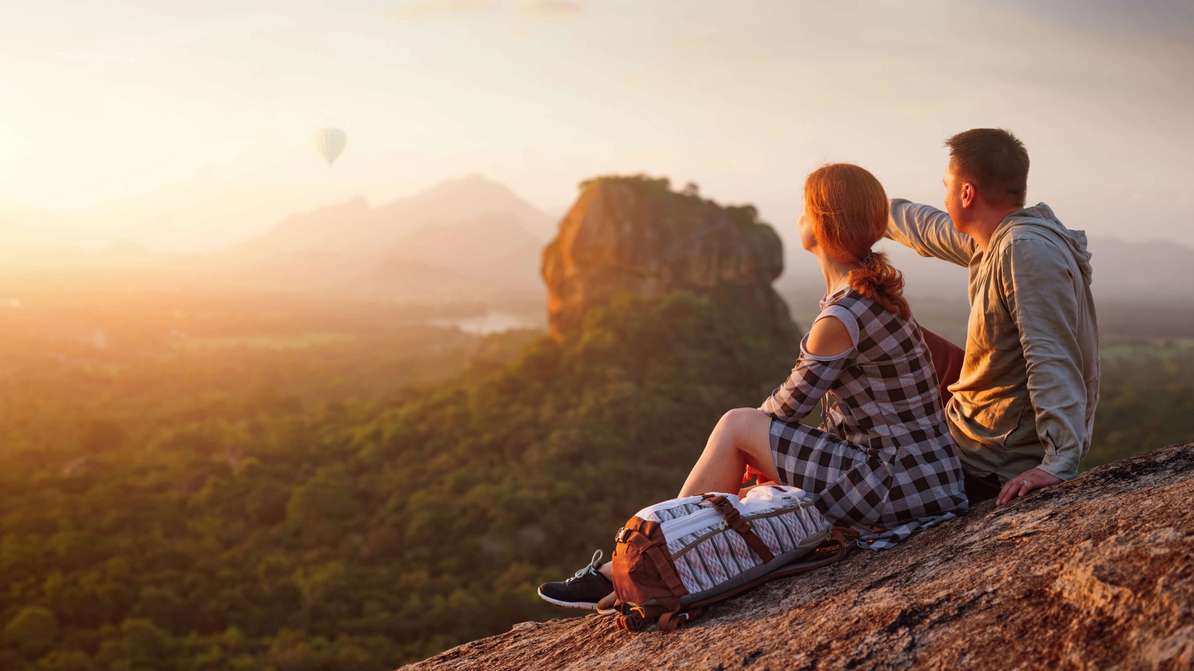 Mladý pár sediaci na kopci pozeracúci na výhľad