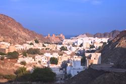 Historická časť Muscatu s bielymi domami, pevnosťou, palácom a pohorím. Omán