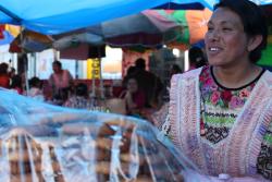 Guatemalská žená vo farebnom kroji ponúka pečivo. Quetzaltenango. Foto: unsplash.com