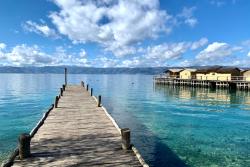 Jazero Ohrid s dreveným mólom a domami na vode.