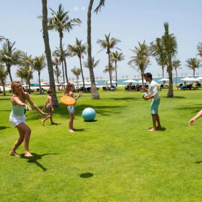 Trávnaté ihrisko pri pláži a skupina ľudí hrajúca sa s loptou v hoteli JA Beach. SAE