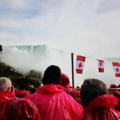 Skupina ľudí na lodi v ružových plášťoch pri vodopáde.