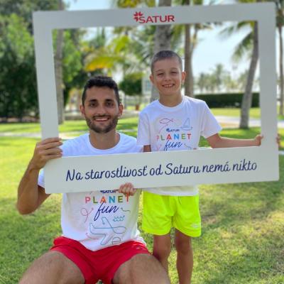 Anímátor Planet FUN s chlapcom na tráve pred hotelom.