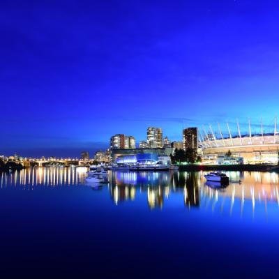 Vysvietené mesto s budovami a odraz na vode.