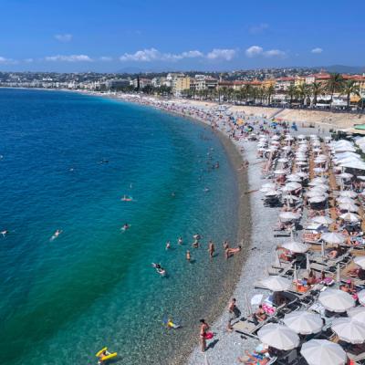 Morské pobrežie a pláž s ľudmi a mesto Nice.