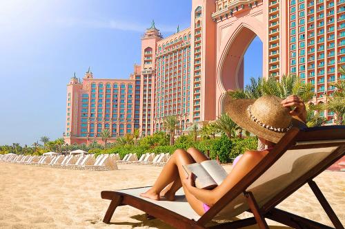 Žena na pláži na lehátku v hoteli Atlantis, The Palm