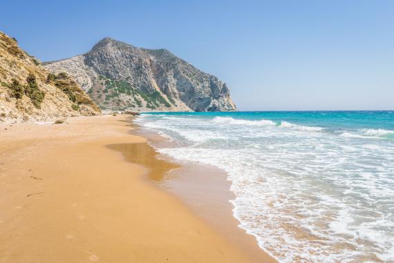 Piesočná pláž s vlnami a útesmi v Grécku