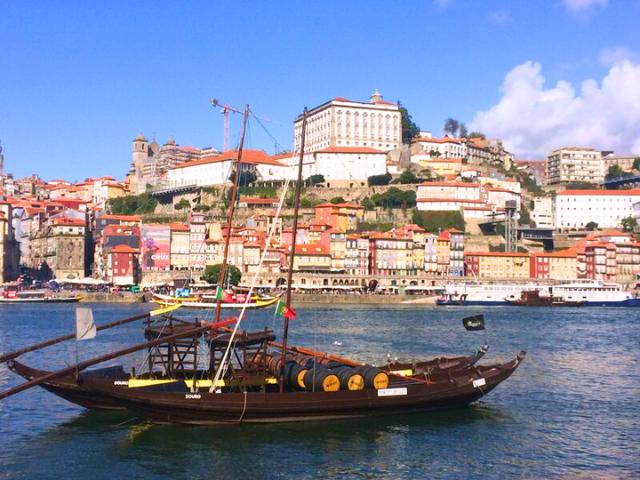 Portugalské Porto, drevená loď na rieke Douro a farebné domy v pozadí.