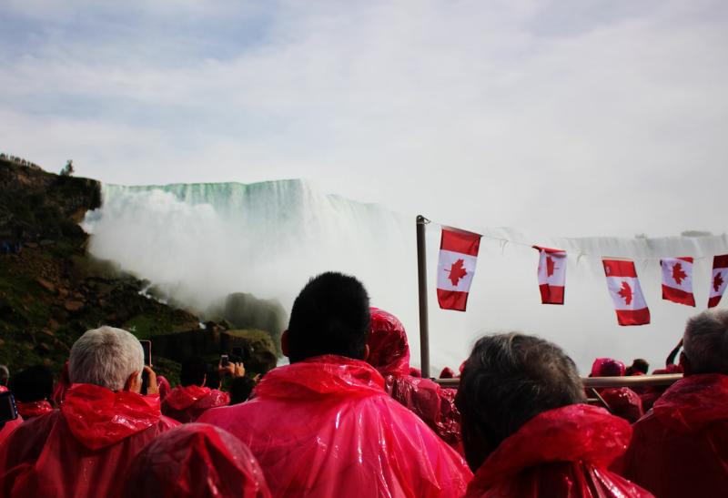 Skupina ľudí na lodi v ružových plášťoch pri vodopáde.