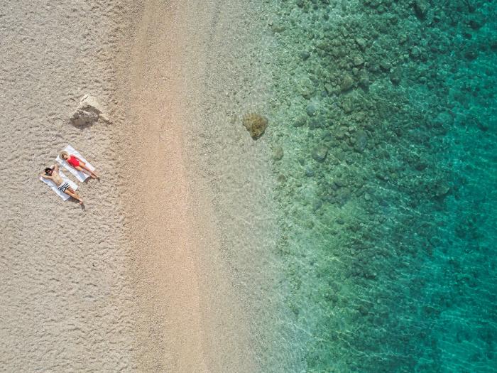 Pár ležiaci na pláži pri mori v Chrovátsku.