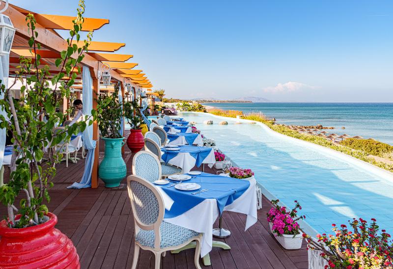 Slnečná terasa so stolmi a stoličkami s výhľadom na more