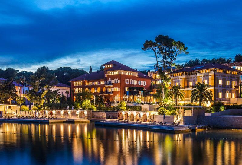 Boutique Hotel Alhambra vysvietený počas noci pri mori v Chorvátsku.