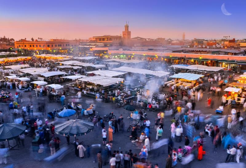 Podvčerné námestie plné ľudí a stánkov v Marrákeši.