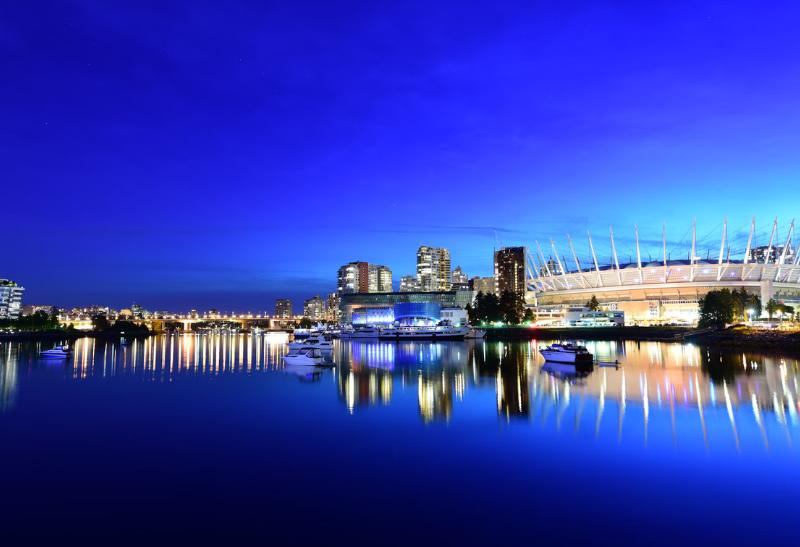 Vysvietené mesto s budovami a odraz na vode.