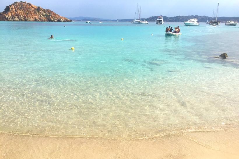 Súostrovie La Maddalena s krásnou pieskovou plážou, blankytným morom a loďkami.