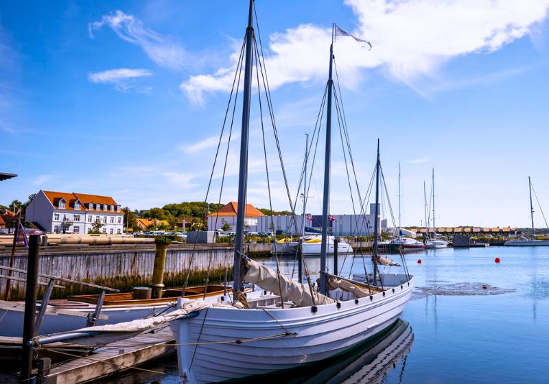 Loď v prístave a domy počas slnečného dňa. Ebeltoft. Dánsko. Foto: unsplash.com