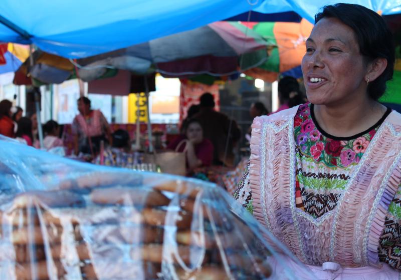 Guatemalská žená vo farebnom kroji ponúka pečivo. Quetzaltenango. Foto: unsplash.com
