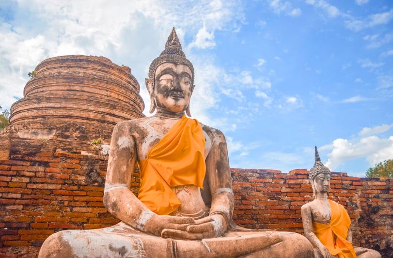 Sediaci Budha pred zbytkami tehlového chrámu v Ayutthayi. Thajsko