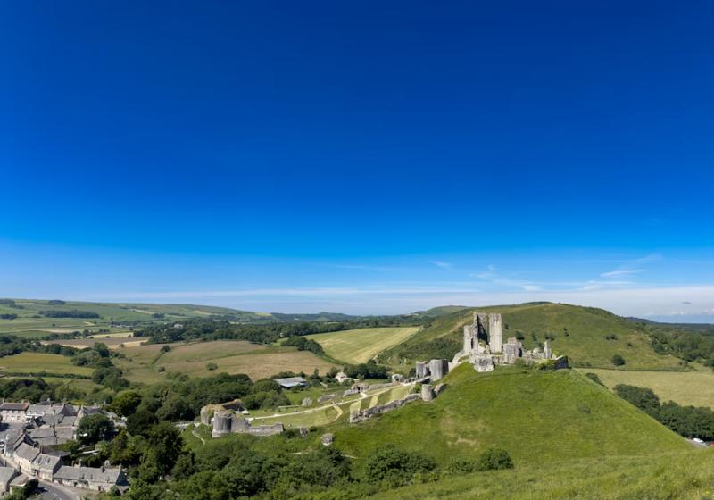 Hrad Corfe a dedina v malebnom kopcovitom teréne Anglicka.