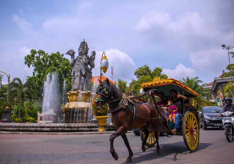 Denpasar a centrum mesta so sochou v centre, kôň a koč s ľudmi. Foto: unsplash.com