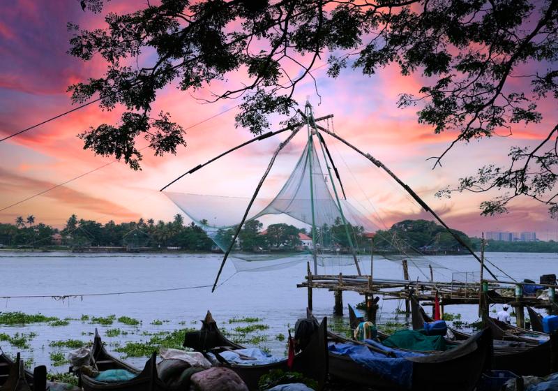 Lode pri vode, pri západe slnka v meste Kochi v Indii.