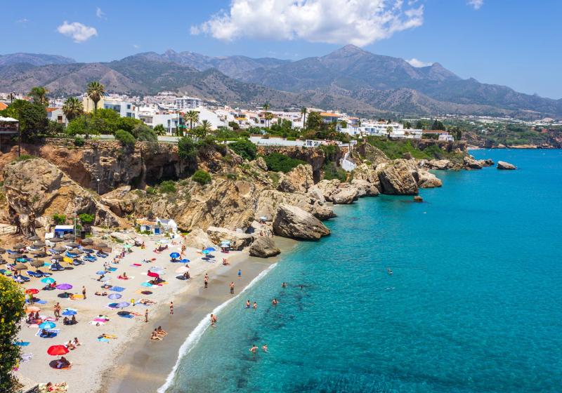 Biele mesto Nerja pri pobreží a piesková pláž