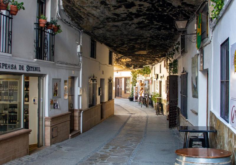 Biele domy, ulica a mohutná skala nad domami.